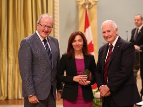 Anna Kapiniari receives, on behalf of her team, the 2014 Public Service Award of Excellence 2014 for Large-Scale Special Event or Project from Governor General David Johnston (R), and  Wayne Wouters, Clerk of the Privy Council.