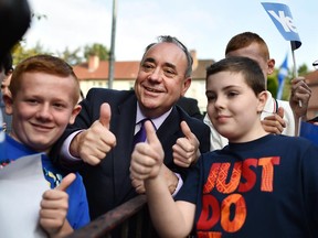 Scotland's First Minister Alex Salmond poses with children during a visit to a housing estate in Glasgow on September 13, 2014.