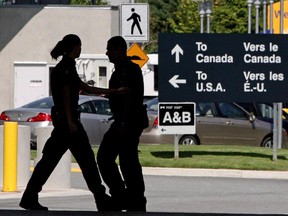 Canadian border guards are silhouetted as they replace each other at an inspection booth at the Douglas border crossing on the Canada-USA border in Surrey, B.C., on August 20, 2009.
