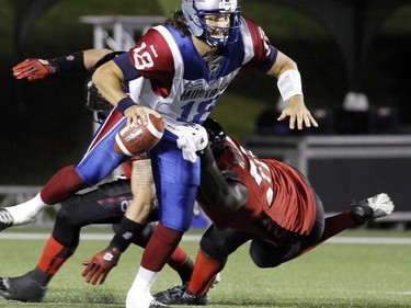 Montreal Alouettes quarterback Johnathan Crompton (18)avoids a sack by Ottawa Redblacks Jonathan Williams (75)during CFL football action between the Ottawa Redblacks and the Montreal Alouettes in Ottawa, Friday September 26, 2014.