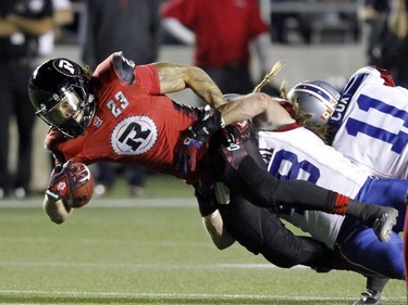 Ottawa Redblacks Jonathan Williams (23) is tackled by Montreal Alouettes Bear Woods (48)during CFL football action between the Ottawa Redblacks and the Montreal Alouettes in Ottawa, Friday September 26, 2014.