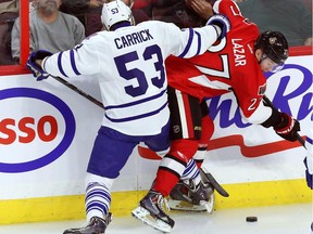 Ottawa Senators forward Curtis Lazar (27) is checked by Toronto Maple Leafs forward Sam Carrick (53) during first period NHL hockey between the Ottawa Senators and the Toronto Maple Leafs in Ottawa Wednesday September 24, 2014.