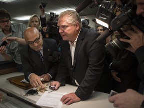 Doug Ford (centre right) submits his papers in Toronto on Friday, September 12, 2014 to enter the mayoral race after the withdrawal of Rob Ford.