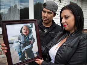 Julie Bilotta is seen here with her spouse Dakota Garlow with a photo of their son Gionni who was born in the Ottawa Detention Centre but died shortly after turning one year old.