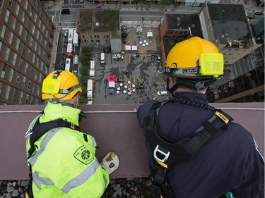 Firefighters look over the edge as as participants rappel from the top of the Morguard Building at 280 Slater Street in the 5th annual Drop Zone Ottawa event which raises money for Easter Seals. September 22, 2014.