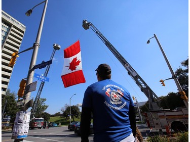 Firefighters raise a giant Canadian flag on Elgin St. at Catherine St. before National Peace Officers Memorial Run to Remember runners arrive in downtown Ottawa, Saturday, September 27, 2014. Police officers ran 460km from Toronto to Ottawa, past Ottawa Police headquarters then up Elgin to Parliament Hill.
