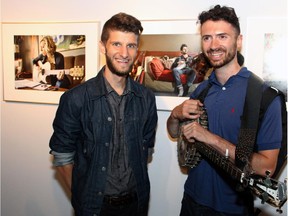 From left, Ottawa photographer Jamie Kronick with local musician Maxim Cossette and the background photograph of him on display during a vernissage held Thursday, Sept. 4, 2014, for Kronick's new show, Songwriter, at the OAG Annex at City Hall.