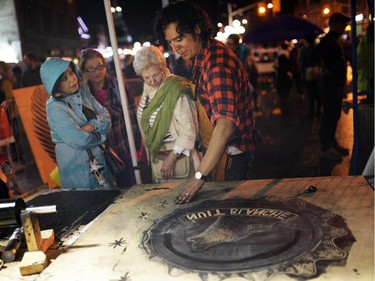 Guillermo Trejo shows people how to cut stencils at the Steamrolling print making project on George St. during Nuit Blanche in Ottawa, on Saturday, September 20, 2014. (
