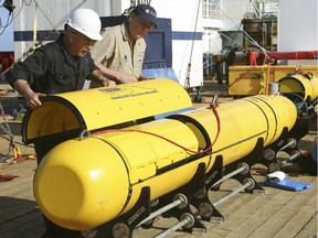 In this Monday, April 14, 2014, photo provided by the Australian Defense Force Phoenix International's Chris Minor, left, and Curt Newport inspect an autonomous underwater vehicle before it is deployed from ADV Ocean Shield in the search of the missing Malaysia Airlines Flight 370 in the southern Indian Ocean.