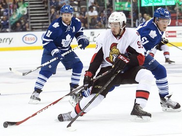 Ottawa Senators forward Mika Zibanejad, centre, gets tied up by Toronto Maple Leafs defenceman Jake Gardiner, right, as forward Phil Kessel looks on during first period pre-season NHL hockey action in Toronto on Wednesday, September 24, 2014.
