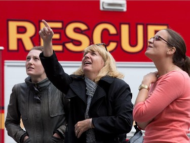 Julia Polnareva, Carla Zylstra, and Brianna Barry watch from the ground as as participants rappel from the top of the Morguard Building at 280 Slater Street in the 5th annual Drop Zone Ottawa event which raises money for Easter Seals. September 22, 2014.