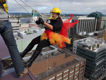 Kathy Dawson steps over the edgeas participants rappel from the top of the Morguard Building at 280 Slater Street in the 5th annual Drop Zone Ottawa event which raises money for Easter Seals. September 22, 2014.