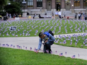 Kevin Liu, a freshman from Texas, places one of 2977 American flags, in the grass at the University of Michigan Thursday, Sept. 11, 2014, in Ann Arbor, Mich., to honor the victims of the Sept. 11 terrorist attacks.