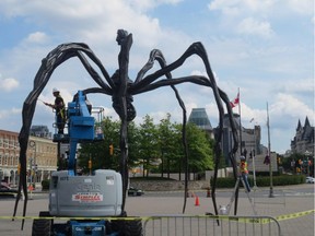 Makeover for Maman: Workers use blowtorches and other tools to trim peeling paint and other imperfections from the Maman statue in front of the National Gallery of Canada on Sept. 4.