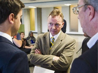 Mayoral candidate, Mike Maguire, center, listens to the debate rules as Ottawa mayor, Jim Watson, right, looks on during an all-candidates mayoral debate at the Carleton University Residence Commons Tuesday September 23, 2014.