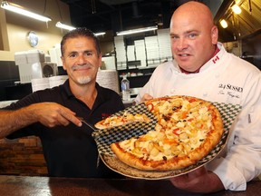 Mazen Kassis, president of Milano Pizzeria, and Tim Wasylko, executive chef at 24 Sussex, display Wasylko's Poutine-Zaa charity fundraising pizza.