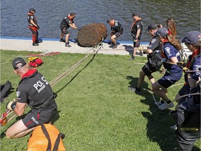 Members of the Ottawa Police Service's Marine, Dive and Trail unit pull up a large 2 x 1.5 metre rusty barrel out of the Ottawa River under the Rideau Canal Locks as part of an initiative with the Great Canadian Shoreline Cleanup in Ottawa Wednesday September 3, 2014.