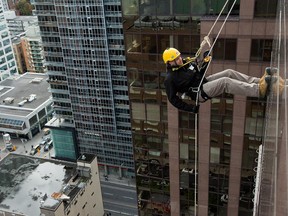 Mike Kilmartin hangs off the rope as as participants rappel from the top of the Morguard Building at 280 Slater Street in the fifth annual Drop Zone Ottawa event which raises money for Easter Seals.