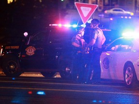 Missouri State Highway Patrol troopers stand posted at the corner of Chambers Road and West Florissant Avenue on Saturday, Sept. 27, 2014, in Ferguson, Mo., as police search for a suspect in the shooting of a Ferguson police officer. Authorities say a police officer has been shot in Ferguson, the U.S. city that has been the scene of unrest since the Aug. 9 shooting of Michael Brown, an unarmed, black 18-year-old, by a white police officer.