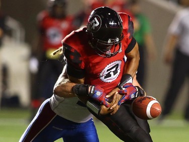Henry Burris #1 of the Ottawa Redblacks fumbles the ball as he is sacked by Bear Woods #48 of the Montreal Alouettes during a CFL game at TD Place Stadium on September 26, 2014.
