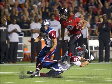 Jonathan Williams #23 of the Ottawa Redblacks hurdles his way to a second quarter touchdown against Chip Cox #11 and Marc-Olivier Brouillette #10 of the Montreal Alouettes during a CFL game at TD Place Stadium on September 26, 2014.