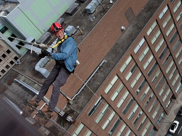 Ottawa Citizen editor Blair Crawford hangs off the rope as as participants rappel from the top of the Morguard Building at 280 Slater Street in the 5th annual Drop Zone Ottawa event which raises money for Easter Seals. September 22, 2014.