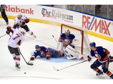 Ottawa Senators Kyle Turris tries to recover a puck as N.Y. Islanders Lubomir Visnovsky slide into his goalie Kevin Poulin during third period pre-season NHL action in St. John's, N.L. on Monday September 22, 2014.