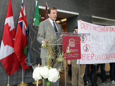 Ottawa University President Allan Rock speaks as a group of student protests express their opinions on high tuition costs in the University of Ottawa's Advanced Research Complex on September 30, 2014 during the official opening.