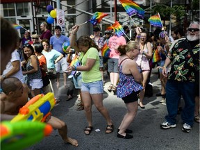 Participants in the Capital Pride Parade spray water at the crowd as they march on Bank Street.