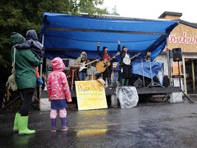 People brave the rain watch a the Elizabeth Riley Band play play in front of Hintonburger, during Taste of Wellington activities on Saturday, September 13, 2014.
