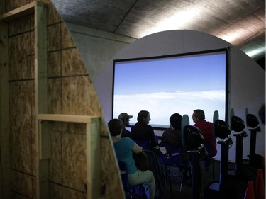 People sit and watch Genevieve Thauvette's flight simulator installation that gives participants an uneasy feeling of flying, under the Plaza Bridge during Nuit Blanche in Ottawa, on Saturday, September 20, 2014.