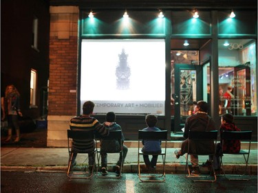 People watch Nick Cave's unique video out front of La Petite Mort gallery during Nuit Blanche in Ottawa, on Saturday, September 20, 2014.