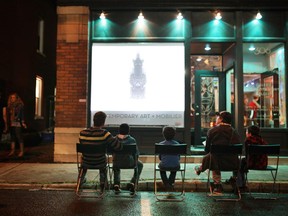 People watch Nick Cave's unique video out front of La Petite Mort gallery during Nuit Blanche in Ottawa, on Saturday, September 21, 2014.