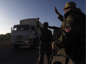 Pro-Russian rebels wave to trucks marked as Russian aid convoy to Ukraine as they return to Russia near the town of Krasnodon, eastern Ukraine, Saturday, Sept. 13, 2014. More than 200 Russian trucks carrying humanitarian supplies entered into Ukraine with supplies for the city of Luhansk, which has for weeks been cut off from electricity and water supplies.