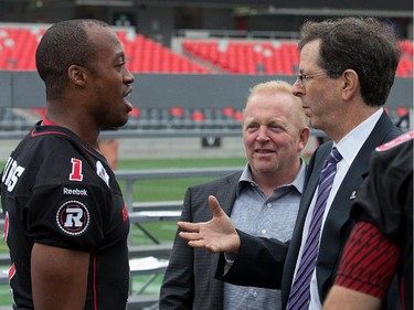 Quarterback Henry Burris chats with Jeff Hunt, centre, and Roger Greenberg, right, as the Ottawa Redblacks had their official team photos taken at TD Place.