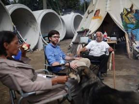 Roger Fleury, of the Quebec Green Party sits around the fire with Alex Tyrrell, leader of the Green Party of Quebec and Audrey Redman the site of the protest in Gatineau on September 10, 2014.