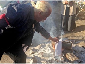 Roger Fleury throws a copy of an injunction ordering protestors off an archeological site in Gatineau into the fire on Thursday.