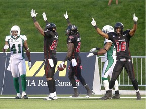 Dobson Collins (80) celebrates scoring a rare touchdown following an onside kick with teammates Wallace Miles (84) and Marcus Henry (16) as Tyron Brackenridge (41) of the Saskatchewan Roughriders looks on.