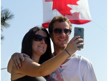 Stephanie Clodd and Joe Cowan take a selfie near where firefighters raised a giant Canadian flag for the National Peace Officers Memorial Run to Remember on Elgin St. at Catherine St. in Ottawa, Saturday, September 27, 2014. Hundreds of police officers ran 460km from Toronto to Ottawa, past Ottawa Police headquarters then up Elgin to Parliament Hill.