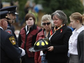 The families of nine Canadian firefighters who died in the line of duty were honoured at the eleventh annual Canadian Firefighter Memorial on Sept. 14, 2014. Barbara Maj, wife of Acting Captain Sylvester Maj, receives a ceremonial helmet for her husband's service.