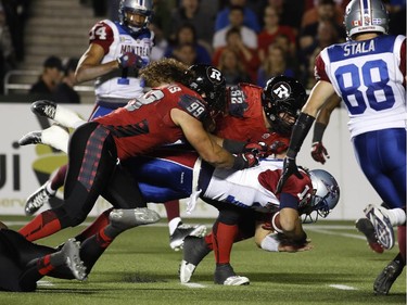 The Montreal Alouettes' Jonathan Crompton dives while getting tackled by Ottawa Redblacks Connor Williams (99) and Zach Evans (92) in CFL action at TD Place on Sept. 26, 2014.