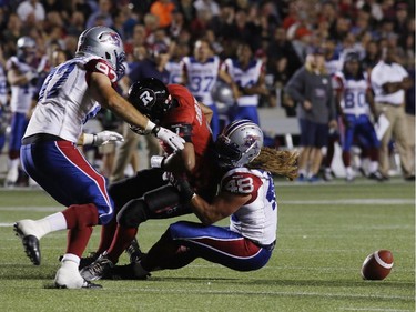 The Ottawa Redblacks' Henry Burris is tackled by the Montreal Alouettes' Bear Woods and fumbles the ball for teammate Aaron Lavarias to recover for a touchdown in CFL action at TD Place on Sept. 26, 2014.