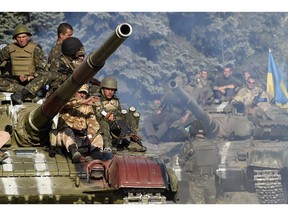 TOPSHOTS Ukrainian army soldiers ride a tank on a road near where pro-Russian separatists fired heavy artillery, on the outskirts of the key southeastern port city of Mariupol, on September 5, 2014. Ukraine and pro-Russian rebels agreed on September 5 on ceasefire aimed at halting nearly five months of war that plunged relations between Russia and the West into their worst crisis since the Cold War.