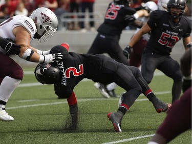 Tunde Adeleke of the Carleton Ravens is tackled hard during the Panda Game against the University of Ottawa Gee-Gees at TD Place on Sept. 20, 2014. The Ravens won the game 33-31 with a hail-mary pass.