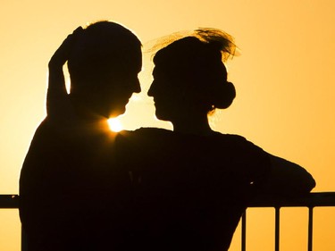 Two people embrace under the setting sun at the 2014 Harvest Noir picnic at 50 Sussex Dr.