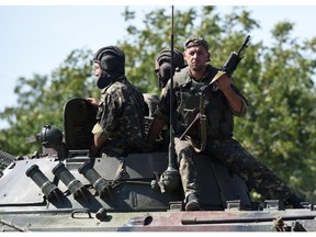 Ukrainian soldiers ride an army vehicule on September 7, 2014 after an overnight bombing attack, on the road to Russia, at an Ukrainian army checkpoint in the outskirts of the key southeastern port city of Mariupol. Gunfire and heavy shelling rocked a key frontline city in eastern Ukraine overnight, raising fears on September 7 that a tenuous truce between government and rebel forces had already collapsed. Numerous explosions rattled the night sky and thick smoke was visible on the horizon of Mariupol, a strategic government-held port city on the Azov Sea in the southeast of the country.