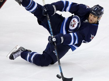 Winnipeg Jets' Adam Pardy (2) plays the puck as he falls against the Ottawa Senators during first period pre-season NHL hockey action in Winnipeg, Tuesday, September 30, 2014.