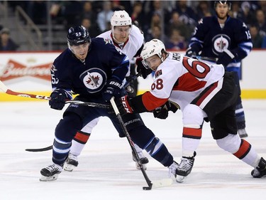 Winnipeg Jets' Mark Scheifele (55) battles with Ottawa Senators' Mark Stone (61) and Mike Hoffman (68) during second period pre-season NHL hockey action in Winnipeg, Tuesday, September 30, 2014.