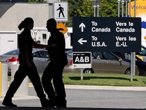 Canadian border guards are silhouetted as they replace each other at an inspection booth at the Douglas border crossing on the Canada-USA border in Surrey, B.C., August 20, 2009. Frustrated by costly delays at the Canada-U.S. border, the business community is urging governments to seek solutions from private-sector whiz kids. THE CANADIAN PRESS/Darryl Dyck