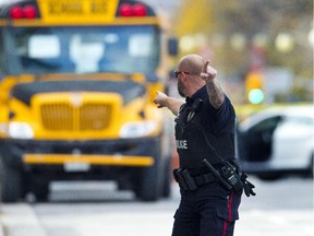 Ottawa Policeman orders traffic including this school bus off Wellington St. A shooter was reported to be shot dead Oct 22 by security at Parliament Hill. A soldier at the War Memorial Cenotaph was shot just moments before.